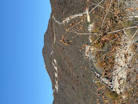       View of the Great Wall of China winding through rugged hills.
  