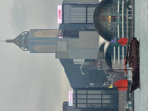       Traditional junk boat sailing in front of modern skyscrapers.
  