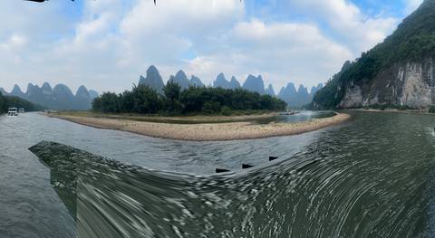 Boat on a river with karst mountains in the background.
