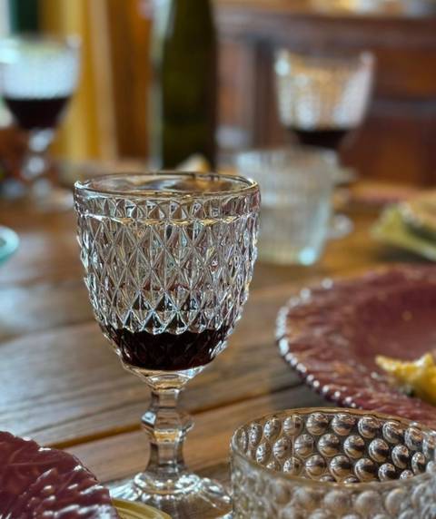 Crystal glass of red wine on a rustic wooden table.