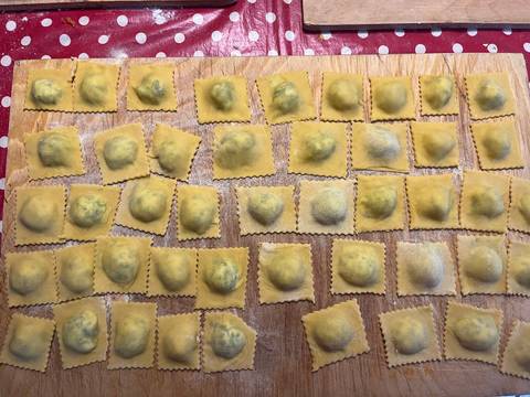 Handmade ravioli laid out on a board, ready to cook.