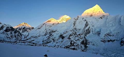 Snow-capped mountains with a golden glow at sunrise.
