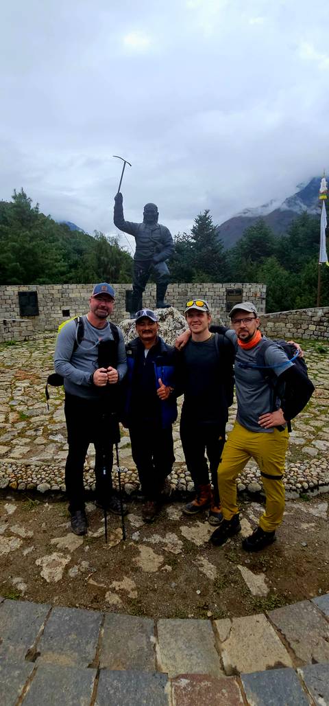 Group of four people posing in front of a statue.