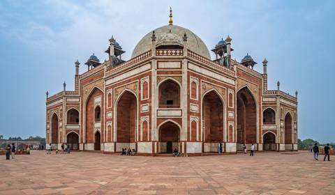       Historic mausoleum with elegant Mughal architecture and people around.
  