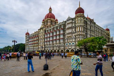 People around an iconic hotel with Indo-Saracenic architecture.