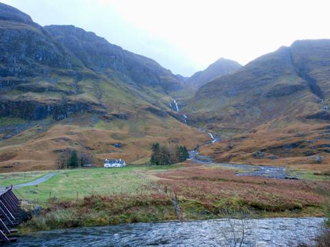 A scenic view of the highlands with a small house surrounded by mountains.