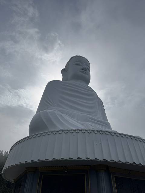 White Buddha statue against a cloudy sky.