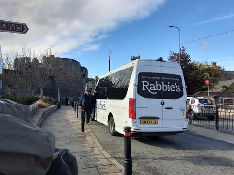 Tourist bus parked near a historic castle.