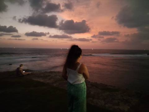       Person standing by the sea during sunset, blurry background.
  