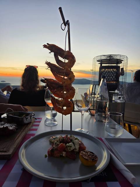 Grilled prawns on skewers with a sunset view.