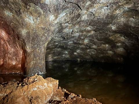 Dark cave with water reflecting the walls.
