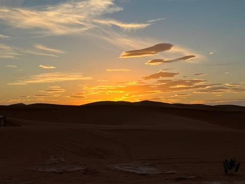 Sunset over sand dunes with a clear sky.