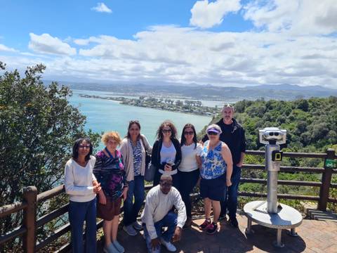 A group of people at a scenic viewpoint overlooking a bay.