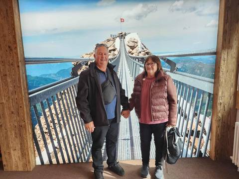 People standing on a bridge with mountains in the background.