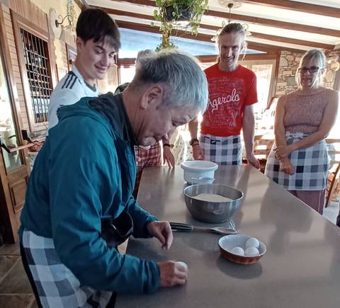 Group of people in a kitchen setting with cooking tools.
