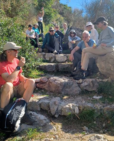 People sitting outdoors on rocks, enjoying a snack.