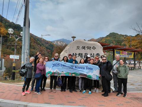 Group of people holding a tour banner in front of mountains.