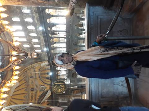 Person standing inside a mosque with decorative elements.