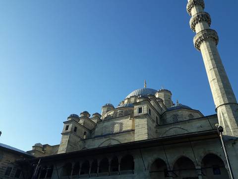 Mosque with numerous domes and a blue sky background.