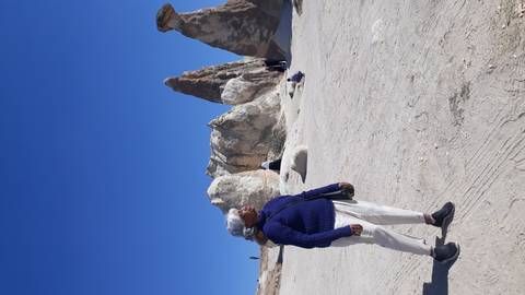       A person standing in front of unique rock formations.
  