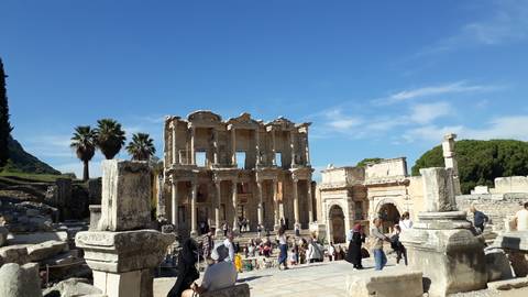       People exploring ancient ruins under a clear sky.
  