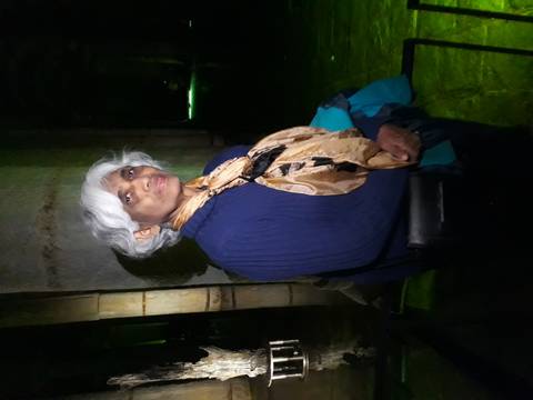 Person standing in a dimly lit ancient interior.