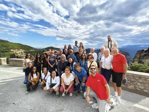 Large group of tourists posing in a scenic mountainous area.