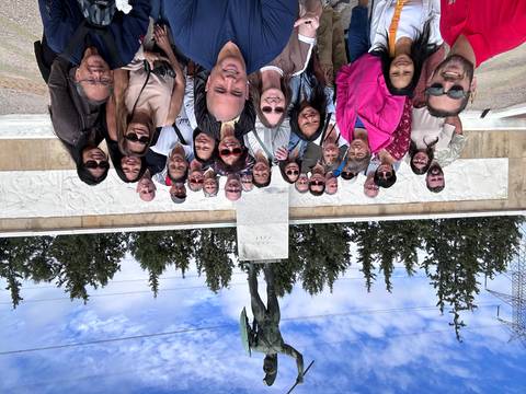 Group of tourists posing in front of a statue and a wall relief.