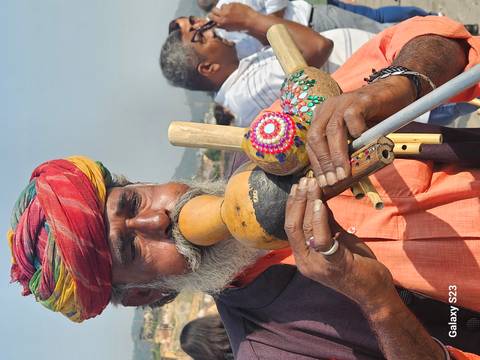 Man playing a traditional instrument in colorful attire.