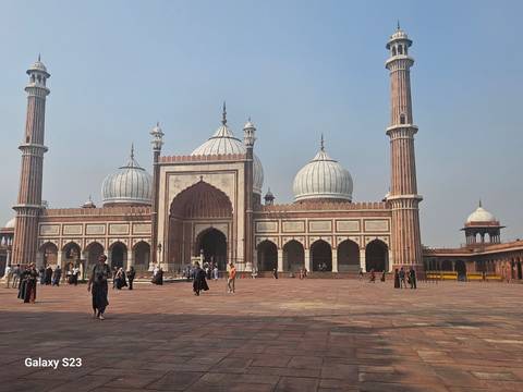       Jama Masjid with people walking in the courtyard.
  