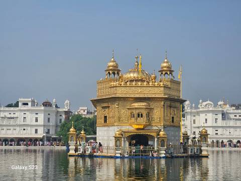       Golden Temple in Amritsar with visitors and reflections in water.
  