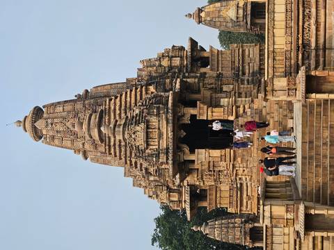 Historic stone temple with intricate carvings and people climbing the steps.