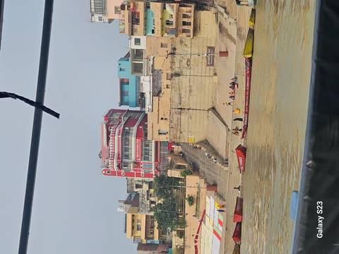       Scene of a riverbank with colorful buildings and boats.
  
