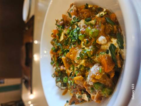       Bowl of colorful curry with herbs on top.
  