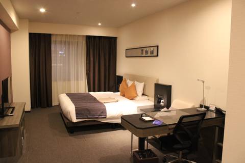 Modern hotel room with double bed and desk.