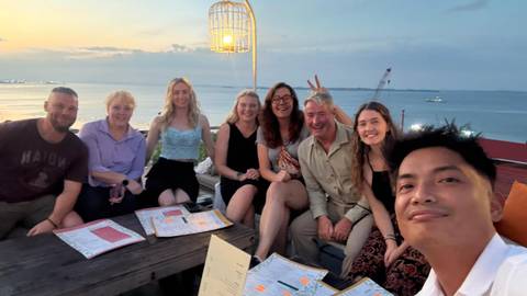 A group of people enjoying a meal together with a sea view.