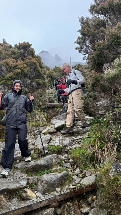       Hikers descending a rocky trail in a mountainous area.
  