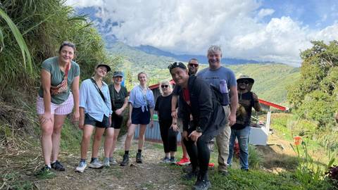       A group of people posing with a mountain landscape in the background.
  