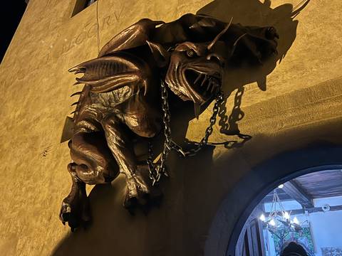 Sculpture of a ferocious gargoyle mounted on a wall at night.