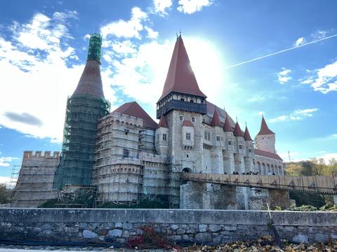 Gothic castle with red rooftops under a bright blue sky.