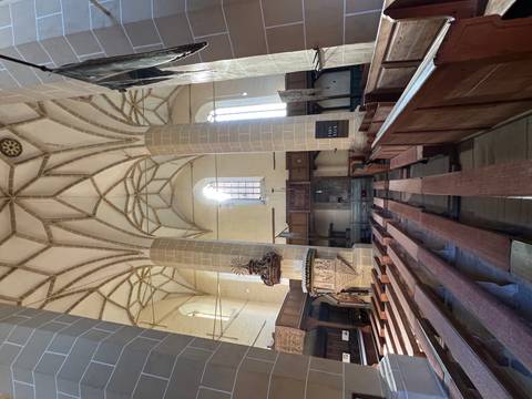 Interior of a Gothic church with vaulted ceilings and wooden pews.