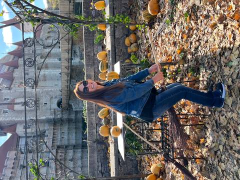 Woman posing playfully with pumpkins in front of a castle.