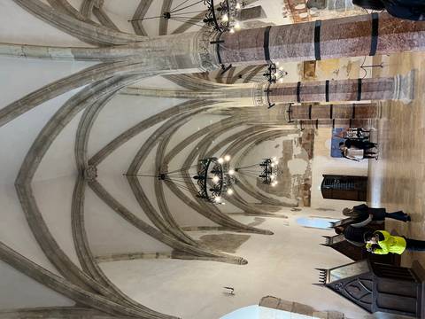       Interior of a historical building with gothic arches and chandeliers.
  