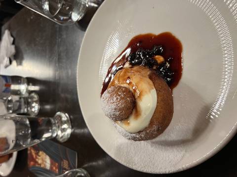       Plate with a dessert topped with cream and sauce in a restaurant setting.
  