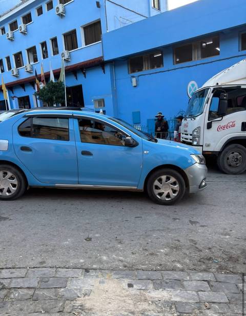       Blue car and a Coca Cola truck on a street in Morocco.
  