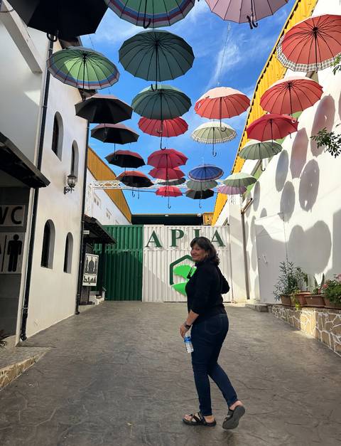 Woman standing under hanging umbrellas outside a building.