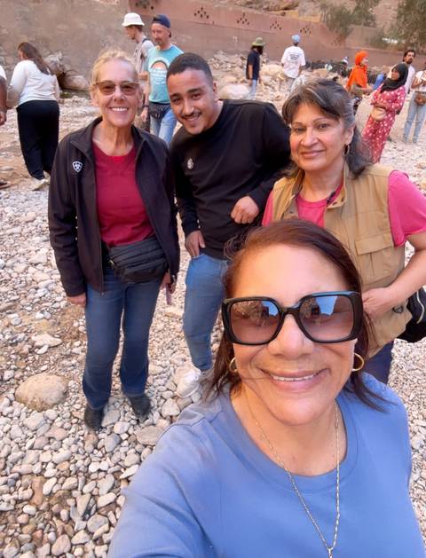 Group selfie of people standing on rocky ground.