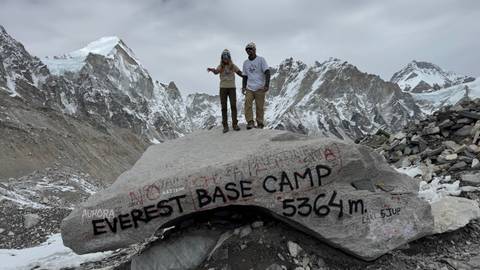 Two people standing in front of a rock labeled Everest Base Camp.