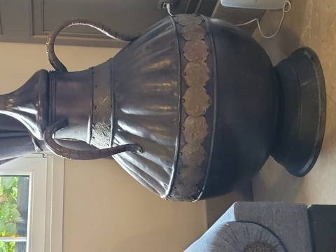       Large metal jug on a floor inside a room.
  