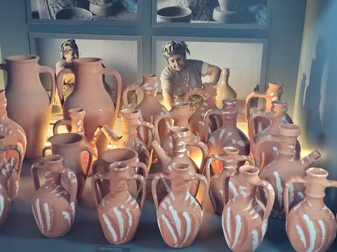 Person crafting with clay jugs in a workshop.